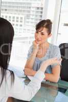 Brunette and black haired co workers chat to one another