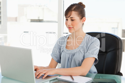 Brunette employee types on her laptop