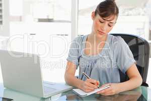 A woman takes down notes on her notepad