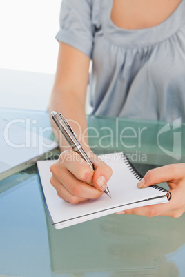 Close up of a woman writing on a notepad
