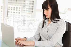 A woman looking at her laptop screen as she types
