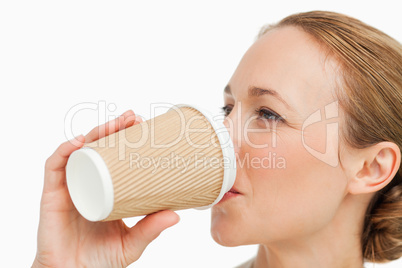 Close-up of a woman in a suit drinking a takeaway coffee