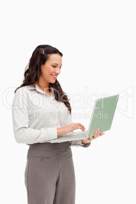 Brunette standing while using a laptop