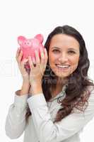 Portrait of a brunette shaking a piggy bank
