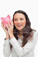 Brunette shaking a piggy bank