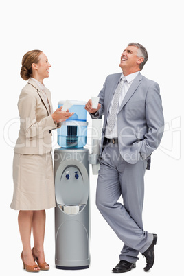 People in suit laughing next to the water dispenser