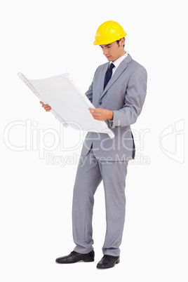 Man in a suit with safety helmet watching plans
