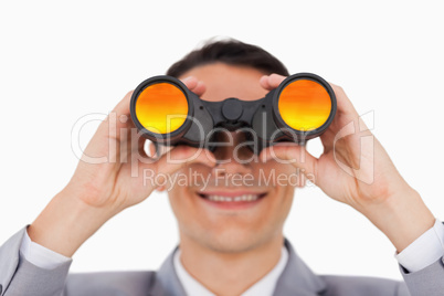 Close-up of a smiling businessman using binoculars