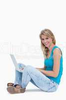 A woman smiling at the camera with a laptop on the leg