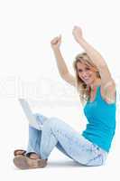 Smiling woman has her arms in the air with a laptop between her