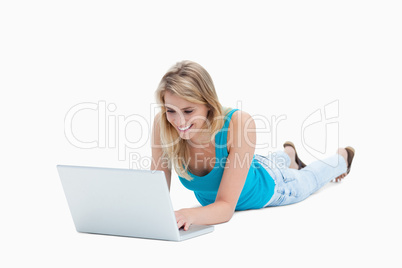 A young woman lying on the floor with a laptop