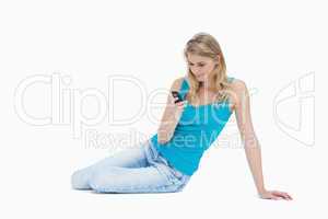 A woman sitting on the floor looking at her mobile phone