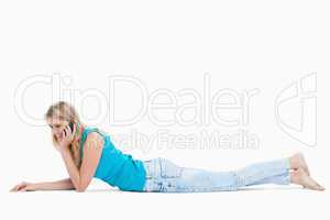 A happy woman lying on the floor is talking on her mobile phone