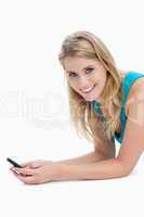 A woman holding a mobile phone is smiling at the camera