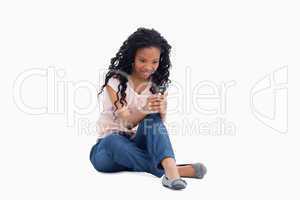 A surprised woman sitting on the floor is texting off her mobile