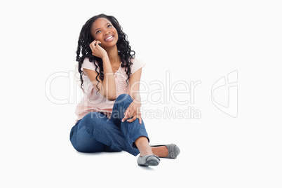 A smiling woman talking on her mobile phone is looking up