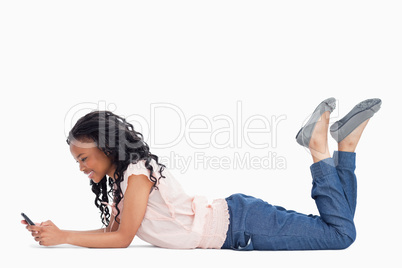 A young woman lying on the ground is texting off her mobile phon