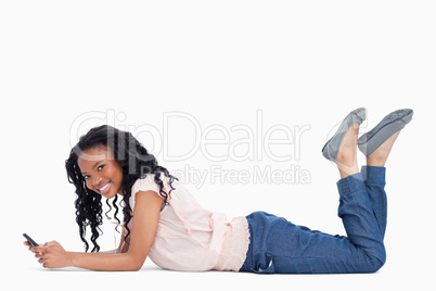 A young woman smiling at the camera is lying on the floor holdin