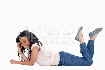 A smiling woman is lying on the floor talking on her mobile phon