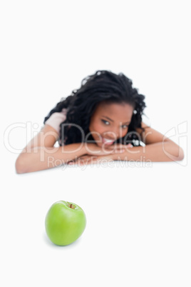 A green apple with a smiling girl in the background