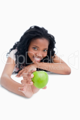 A young girl is holding a green apple out in front of her