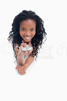A young woman pointing a television remote at the camera
