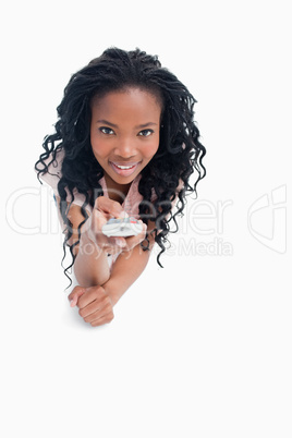 A smiling young girl is pointing a television remote at the came