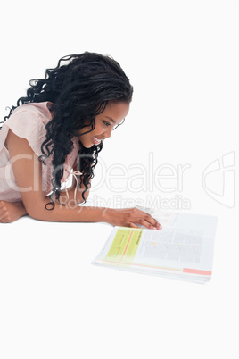 A side shot of a woman lying on the floor reading a book