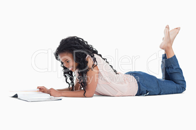 A young woman lying on the floor reading a magazine