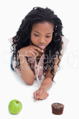 A woman choosing between an apple or a bun