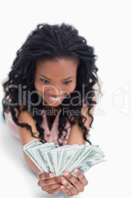 An excited young woman is holding American dollars in her hands