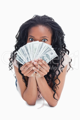 A woman is holding American dollars up to her face