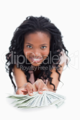 A smiling woman is holding American dollars out in front of her