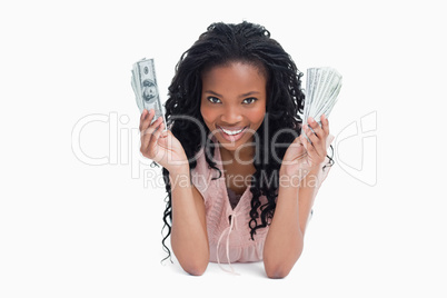 A young woman is holding American dollars and smiling at the cam