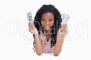 A young woman is holding American dollars and smiling at the cam