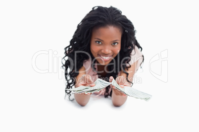 A young woman lying on the floor is holding American dollars out