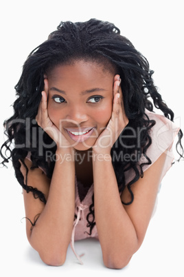 A girl resting her head on her hands is lying on the floor