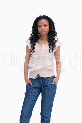 A serious young woman stands with her hands in her pockets