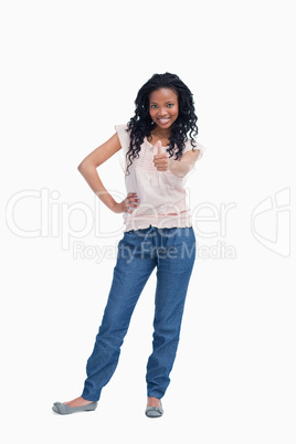 A young woman is standing with her thumb up and her hand on her