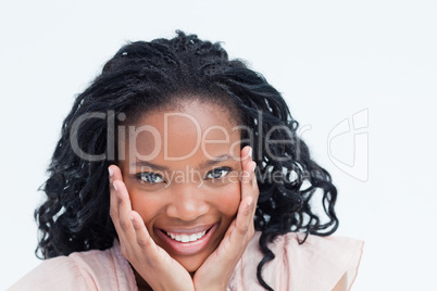 Head shot of a smiling young woman holding her head in her hands