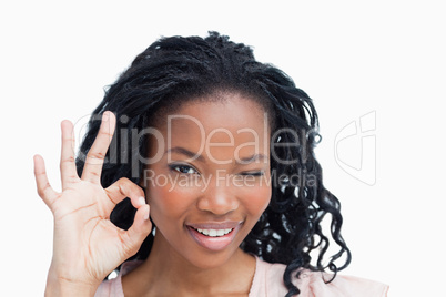 A young woman winking and holding her hand in the okey sign