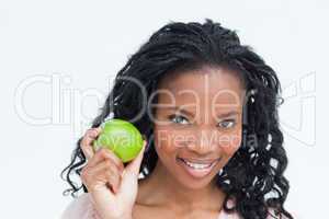 A smiling young woman holding an apple up longside her face