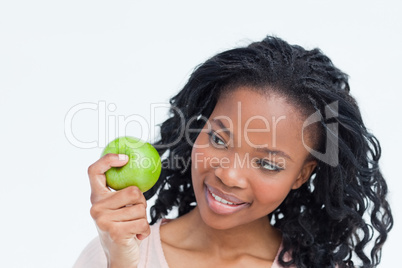 A woman is looking at an apple she is holding