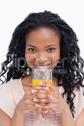 A young woman holding a glass of orange juice with her both hand
