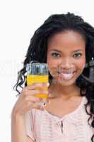 Close up of a smiling young woman holding a glass on orange juic