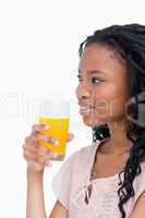 A side shot of a girl holding a glass of orange juice