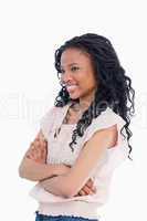 A smiling young woman with her arms folded looking away from the