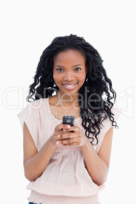 A beautiful woman looking at the camera is holding a mobile phon