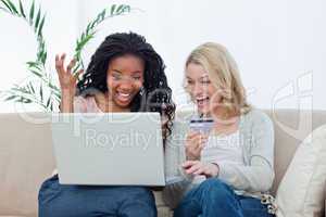 Two laughing women with a laptop and a bank card