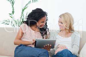 A woman holding a tablet computer is smiling at her friend